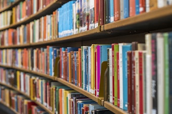 A wall of shelves filled with colorful books in a library.