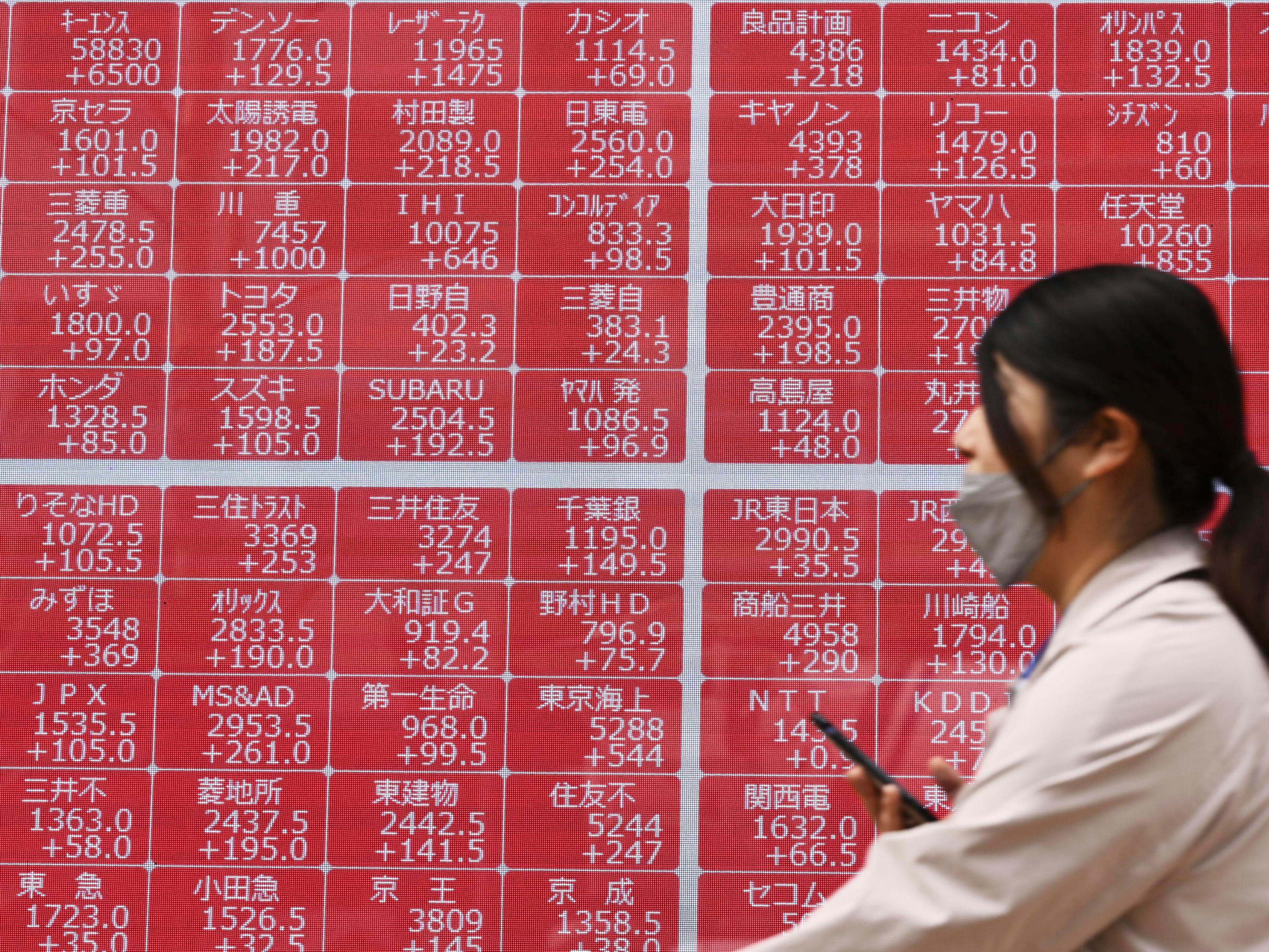caption: A person walks past an electronic stock board at a securities firm in Tokyo on Thursday.