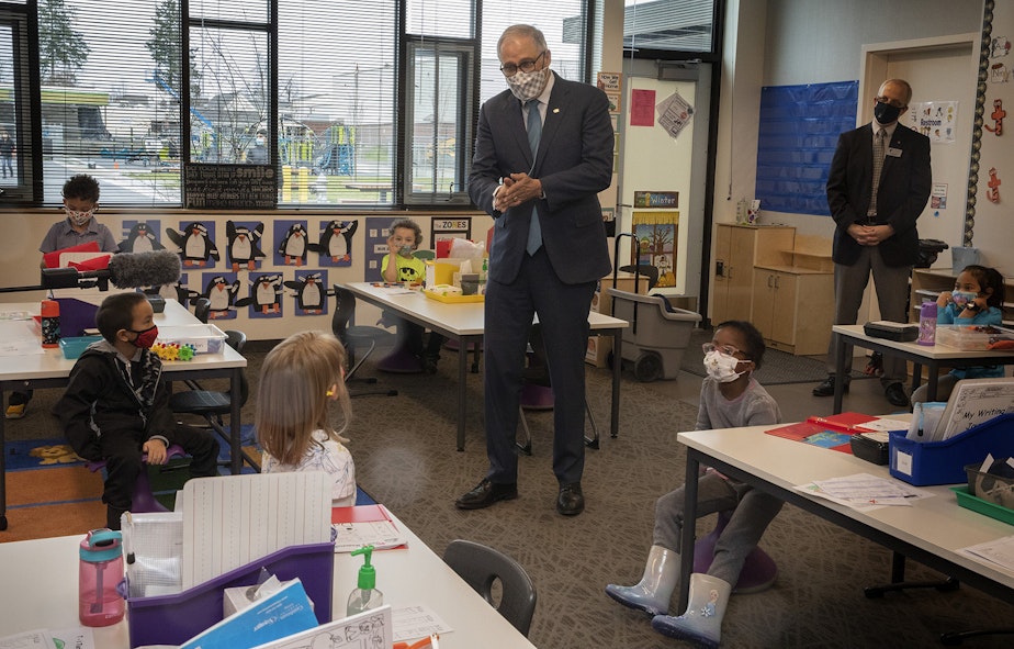 caption: Washington Gov. Jay Inslee speaks with kindergartners in Chelsea Singh's class during a visit to Firgrove Elementary School in Puyallup, Wash., Thursday, Feb. 18, 2021. Students are back in school and all teachers and students are wearing masks. 