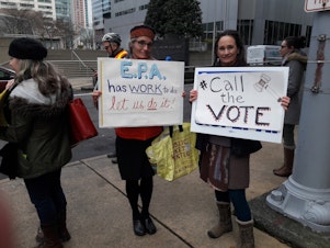 caption: Linda Storm and Elly Hale show off their signs at the rally on Thursday January 17th. They are both eager to get back to work. 