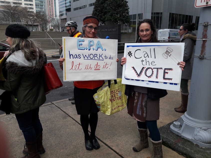 caption: Linda Storm and Elly Hale show off their signs at the rally on Thursday January 17th. They are both eager to get back to work. 