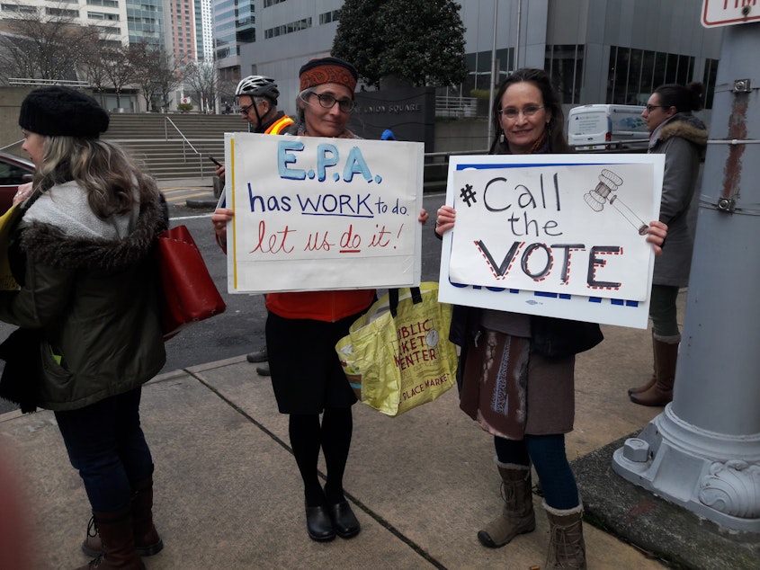 caption: Linda Storm and Elly Hale show off their signs at the rally on Thursday January 17th. They are both eager to get back to work.