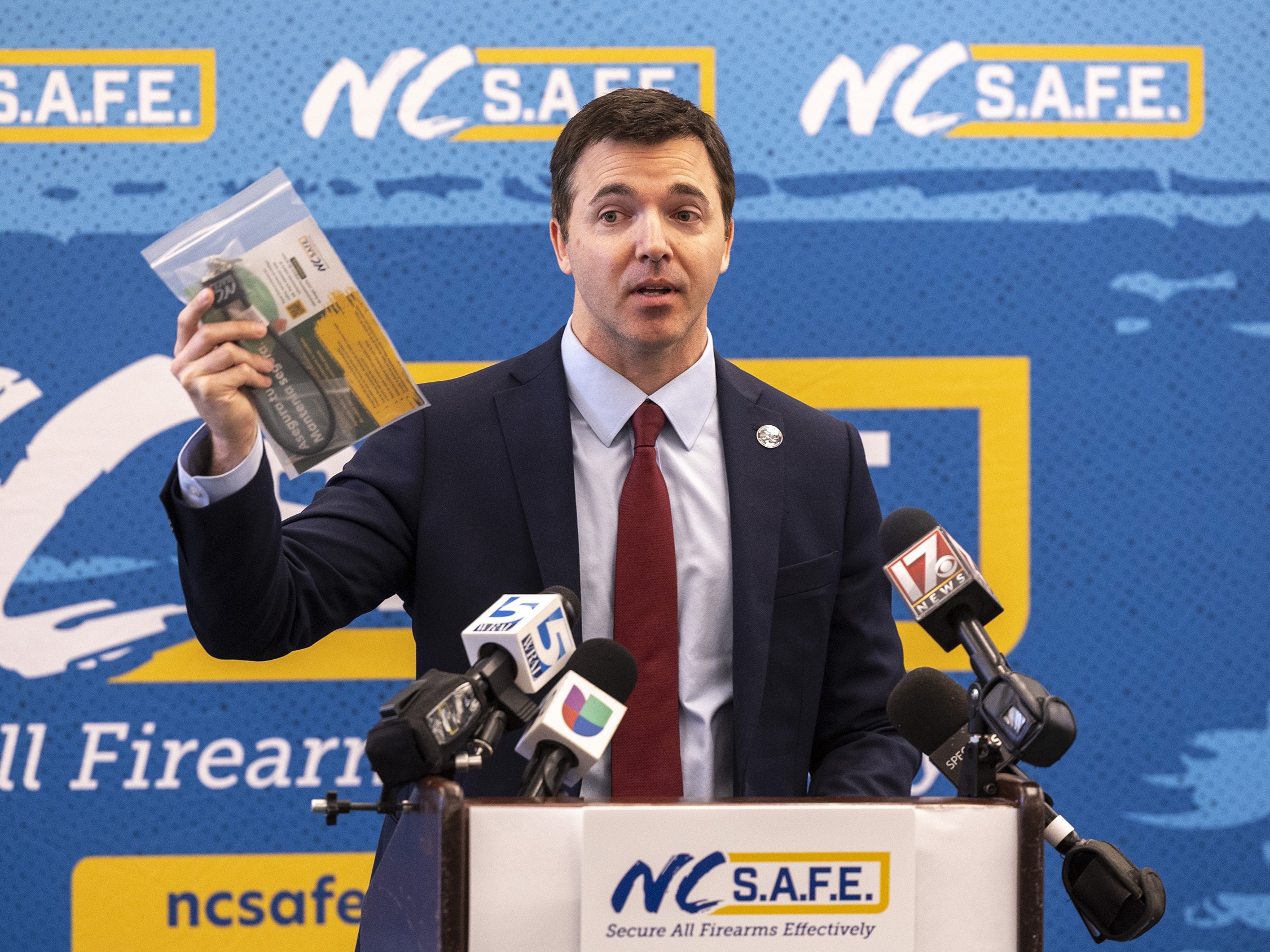 caption: N.C. Attorney General Jeff Jackson holds a gun lock at an event about safe storage of firearms. North Carolina is among 30 states with the most permissive gun laws, according to a new study.