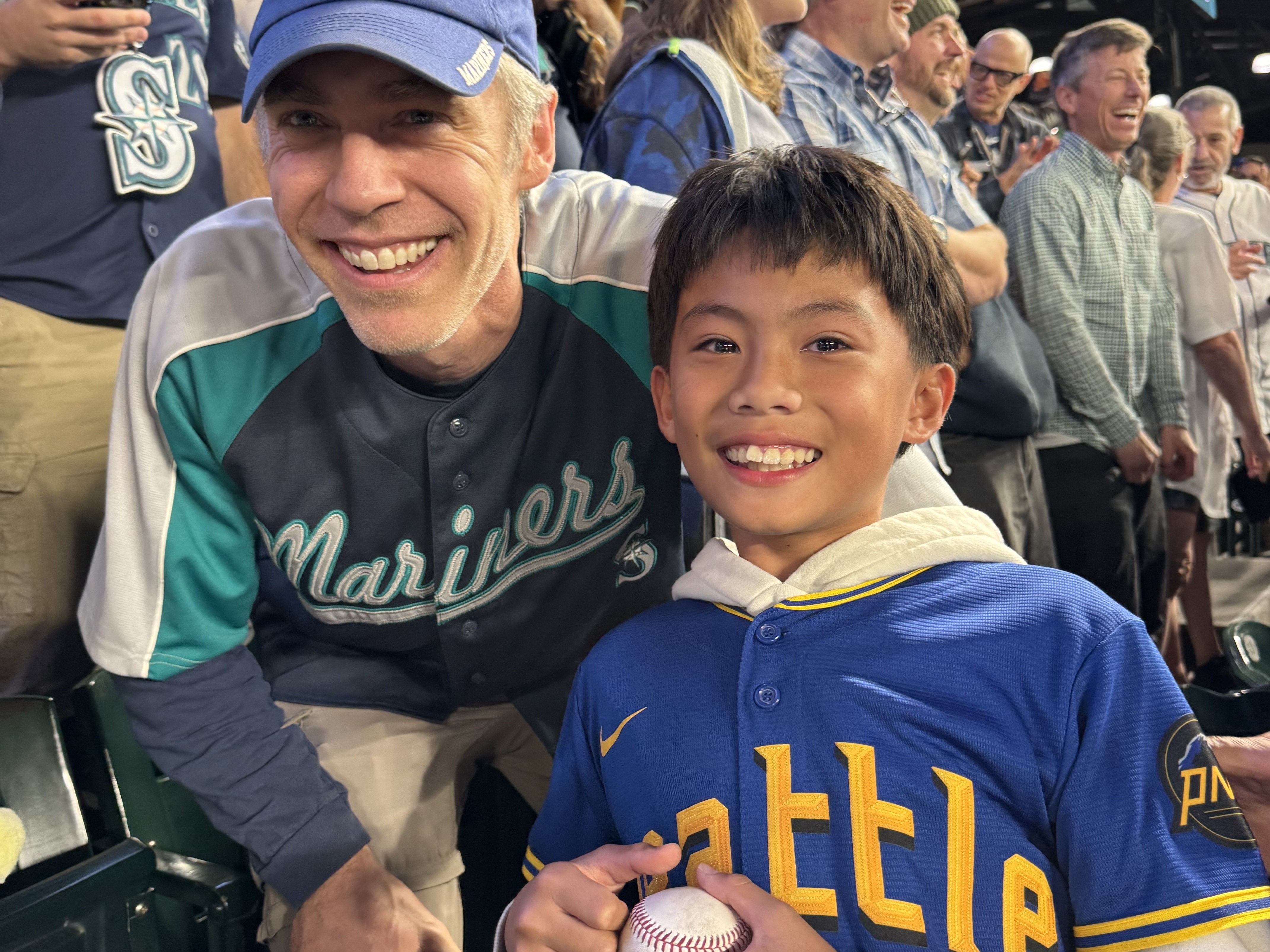 caption: A Mariners fan identified as Glenn Mutti-Driscoll gifted a history-making ball to 12-year-old Marcus Ruelos.