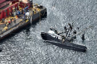 caption: A diesel sheen spreads from the Aleutian Isle, newly lifted to the surface by a crane Sept. 17, five weeks after sinking off San Juan Island.