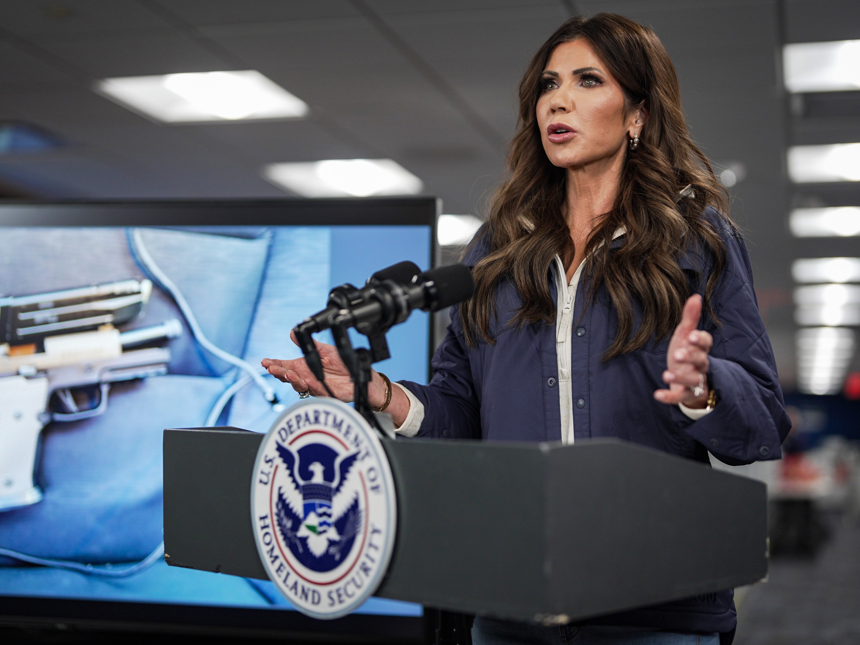 caption: A photograph of the pistol recovered by immigration agents after a shooting in Minneapolis is shown on a screen behind U.S. Secretary of Homeland Security Kristi Noem as she speaks during a news conference in Washington, D.C., on Jan. 24. Federal immigration agents shot and killed Alex Pretti that day during operations in Minneapolis.