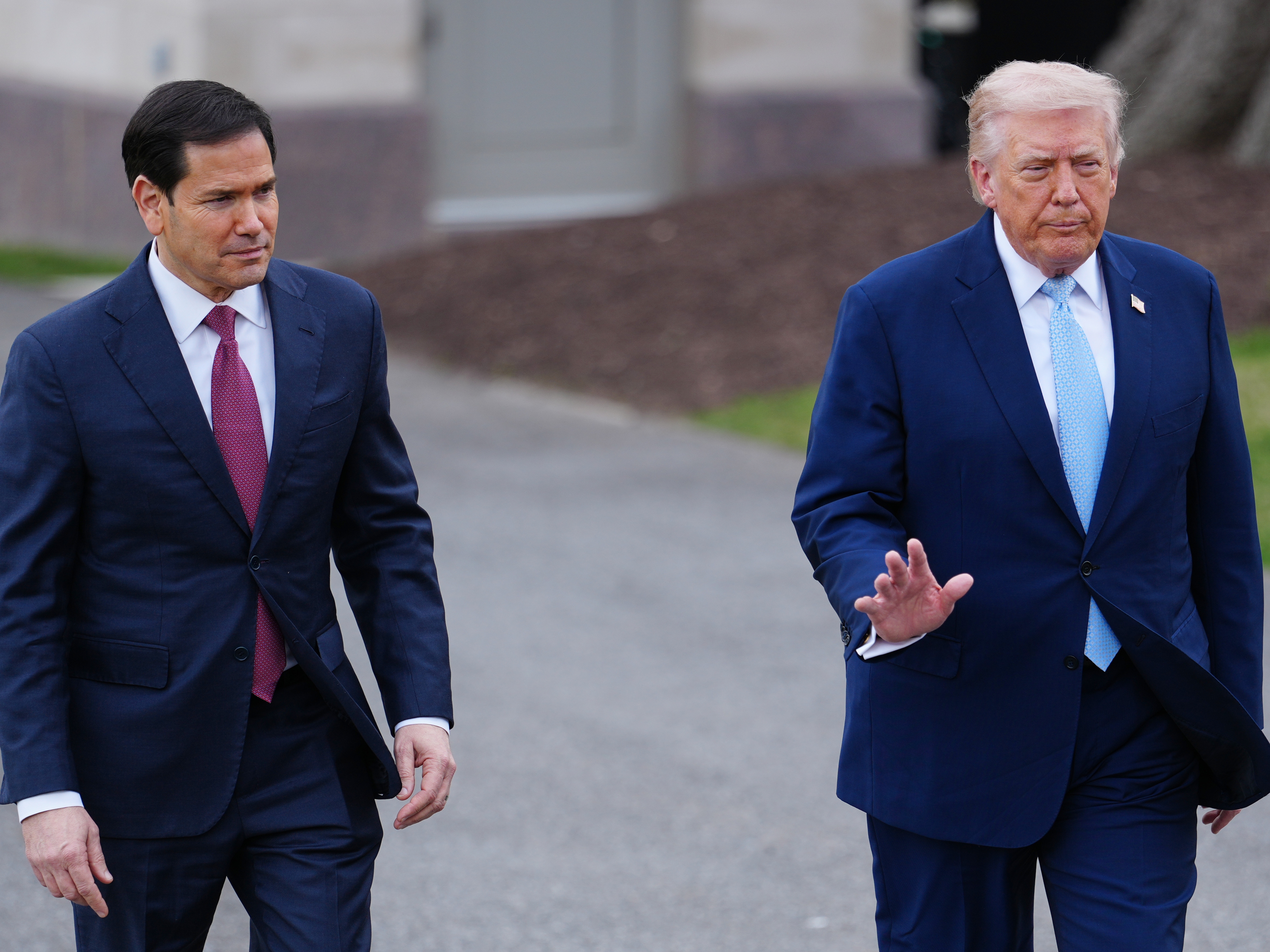 caption: President Trump walks with Secretary of State Marco Rubio to speak with reporters before departing on Marine One from the South Lawn of the White House, March 20.