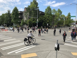 caption: An all-way crosswalk — with people walking straight-across and diagonally — at 15th Avenue Northeast and Northeast 40th Street in Seattle's University District.