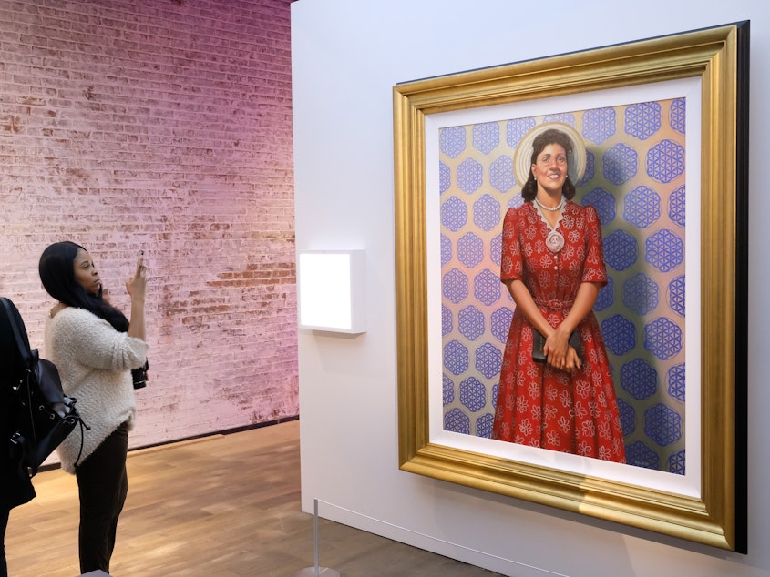 caption: Attendees gaze at a painting of Henrietta Lacks at HBO's The HeLa Project Exhibit for <em>The Immortal Life of Henrietta Lacks</em> in 2017 in New York City.