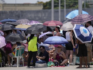 caption: Taylor Swift fans wait for the doors of Nilton Santos Olympic stadium to open for her Eras Tour concert amid a heat wave in Rio de Janeiro, Brazil, Saturday, Nov. 18, 2023. A 23-year-old Taylor Swift fan died Friday night after suffering from cardiac arrest due to heat at the concert, according to a statement from the show's organizers in Brazil.
