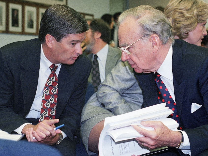 caption: Media magnate Rupert Murdoch, right, huddles with Preston Padden, president of network distribution for Fox, during a hearing of the Federal Communications Commission in May 1995. A generation later, Padden says Murdoch is unfit to hold the licenses for local television stations due to Fox News.