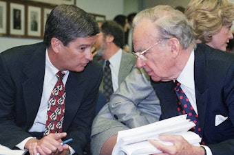 caption: Media magnate Rupert Murdoch, right, huddles with Preston Padden, president of network distribution for Fox, during a hearing of the Federal Communications Commission in May 1995. A generation later, Padden says Murdoch is unfit to hold the licenses for local television stations due to Fox News.