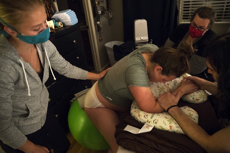caption: From left, doula Solrun Heuschert, midwife Jenn Linstad, right, and Jake Black support Hope Black as she labors at 3:09 a.m. on Friday, May 28, 2020, at their home on Vashon Island.