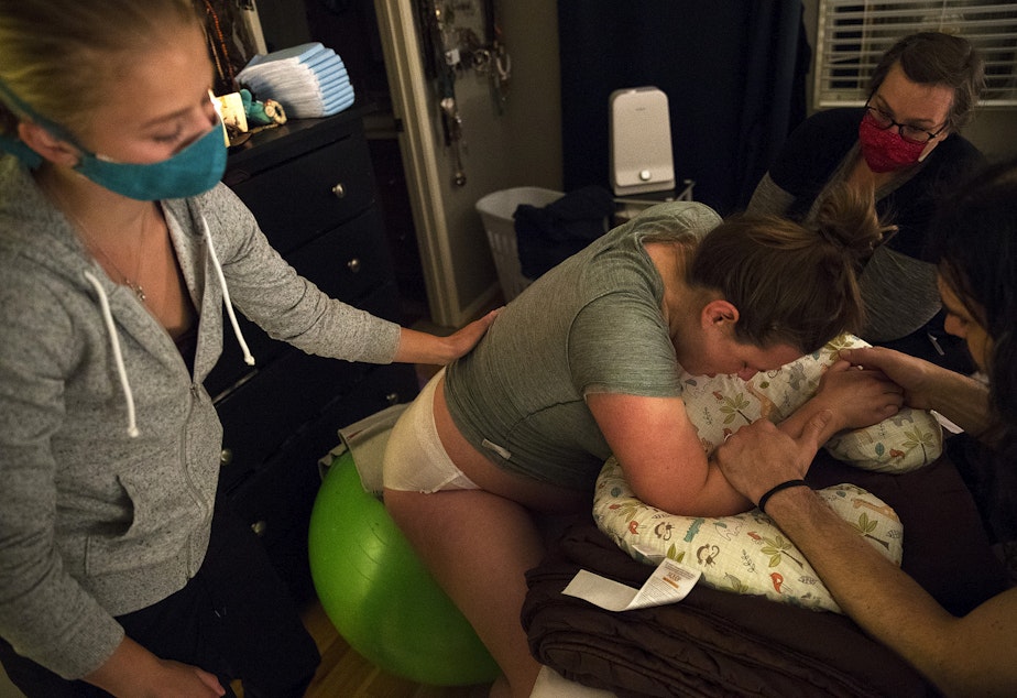 caption: From left, doula Solrun Heuschert, midwife Jenn Linstad, right, and Jake Black support Hope Black as she labors at 3:09 a.m. on Friday, May 28, 2020, at their home on Vashon Island.
