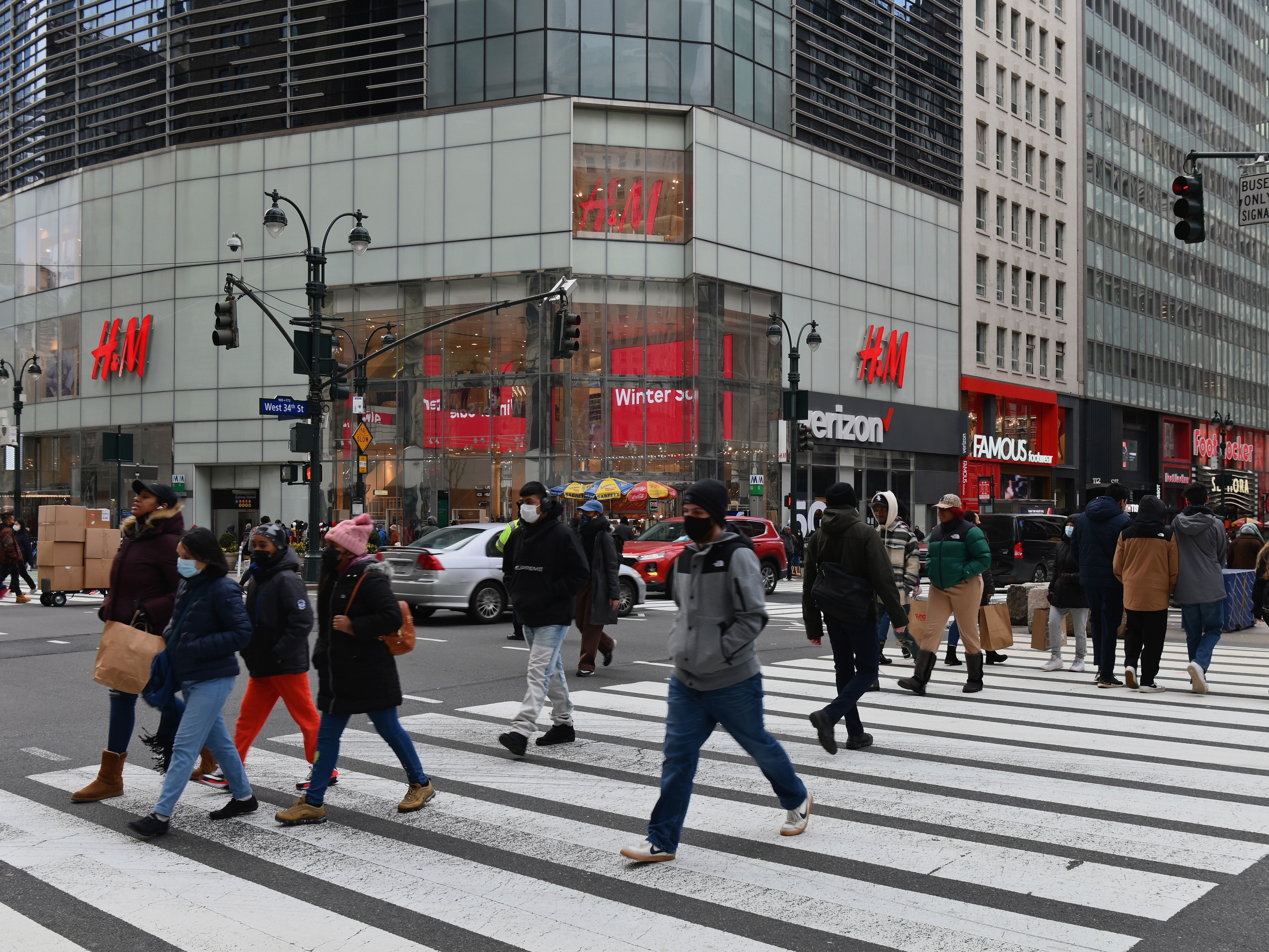 caption: People walk in front of stores in New York's Herald Square on Jan. 8, 2021.