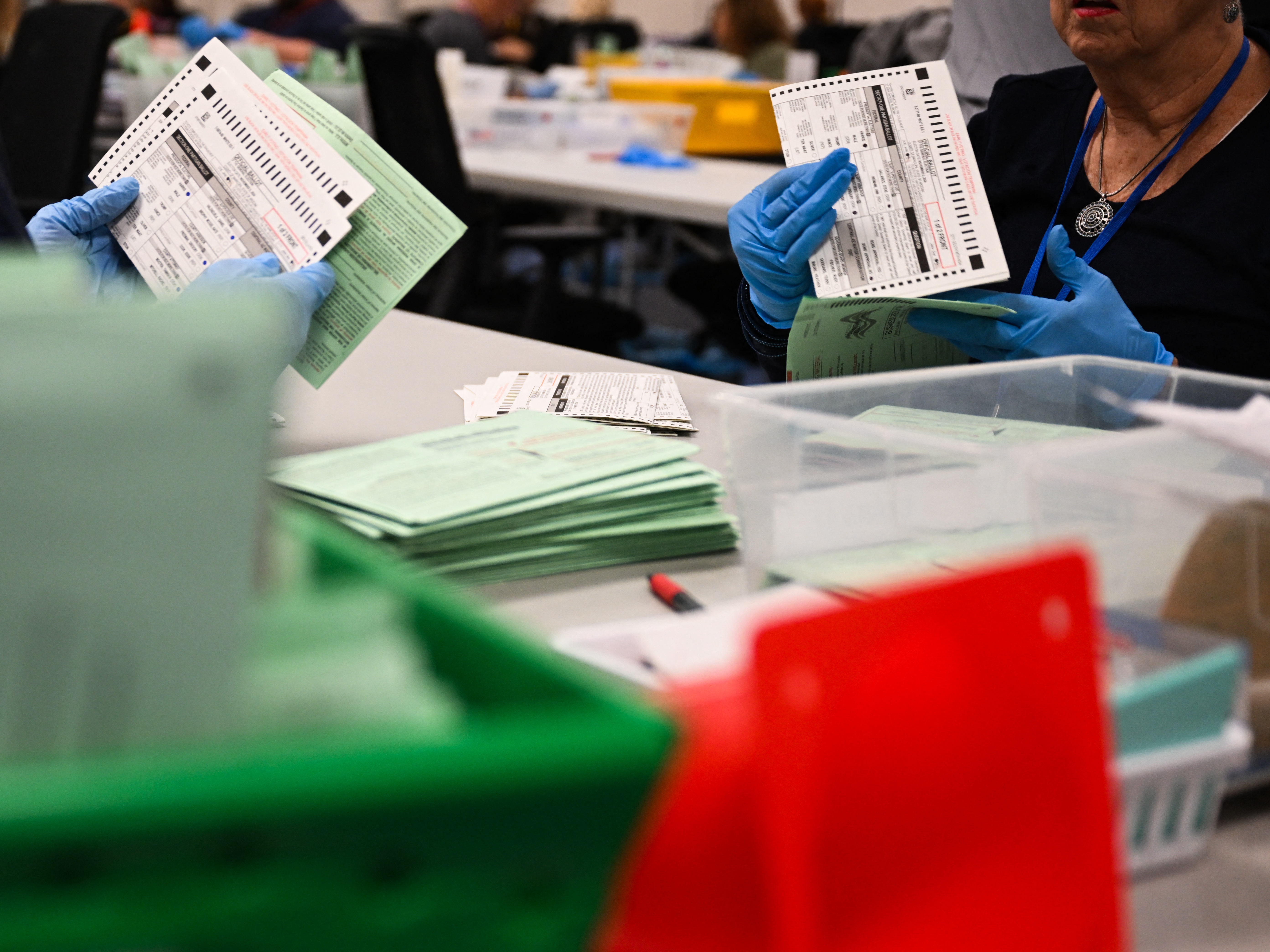 caption: Election workers open and inspect mail-in ballot envelopes for Arizona's 2024 general election inside the Maricopa County Tabulation and Election Center in Phoenix.
