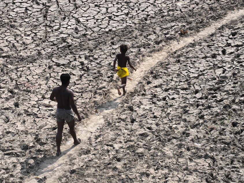 caption: A man and a boy walk across the almost dried up bed of river Yamuna following hot weather in New Delhi, India, May 2, 2022.