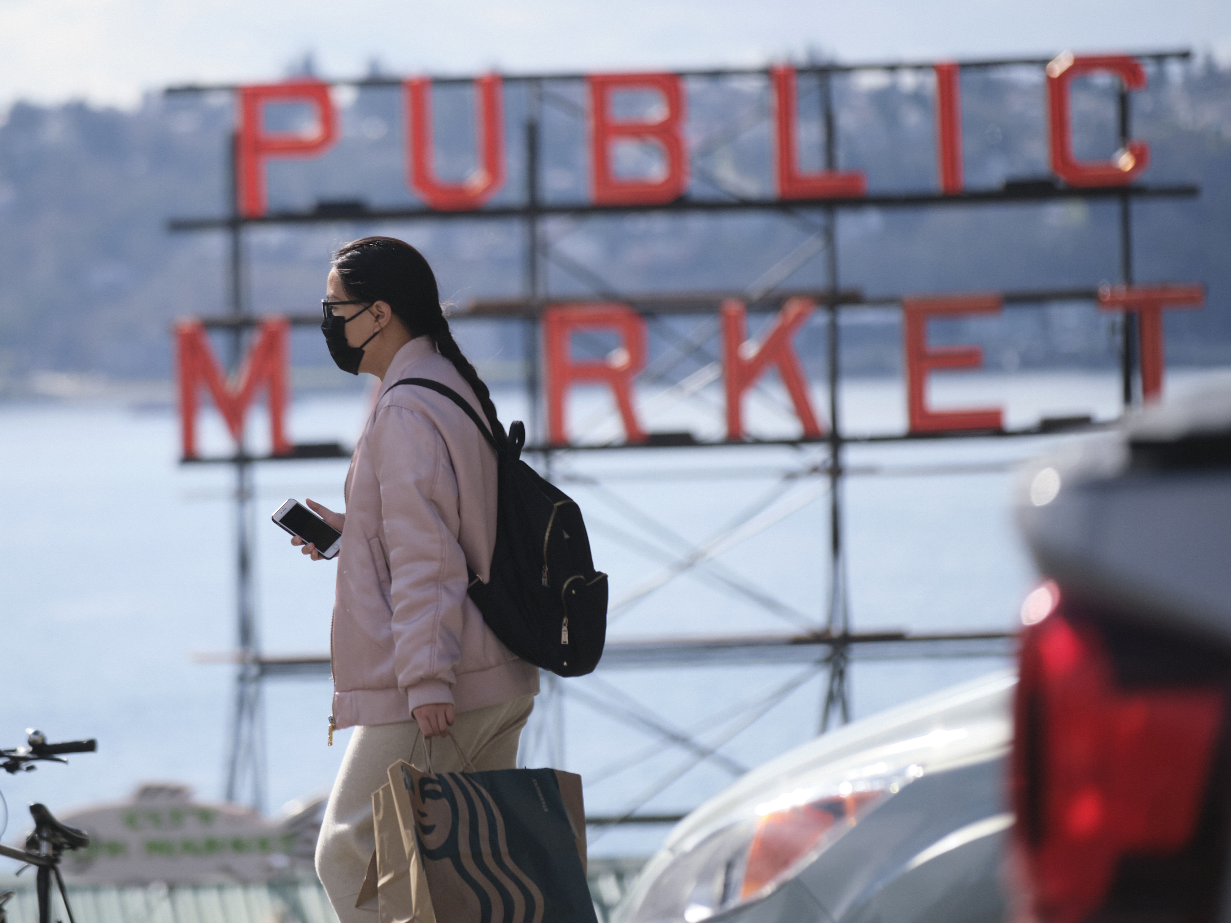 caption: A passerby near the the Pike Place Public Market in Seattle on Wednesday. Washington is one of the states closing schools and other public gathering places to help fight the coronavirus.