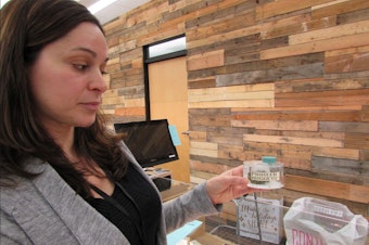 caption: Maria Moses of Dockside Cannabis in Shoreline, Washington, shows off a jar where customers can smell a marijuana sample.