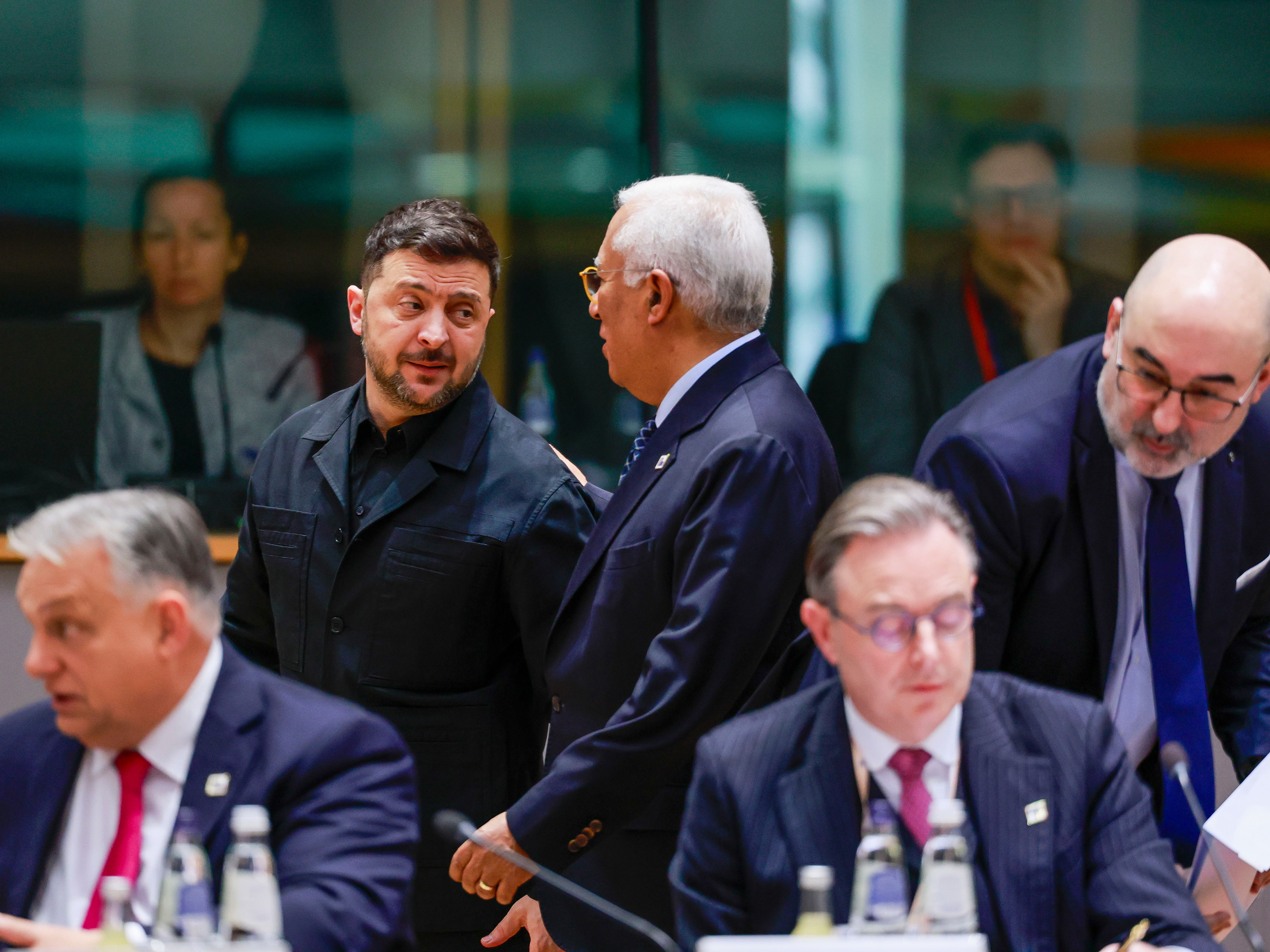 caption: Ukraine's President Volodymyr Zelenskyy, second left, speaks with European Council President Antonio Costa, center rear, during a round table meeting at the EU Summit in Brussels, Thursday, Dec. 18, 2025.