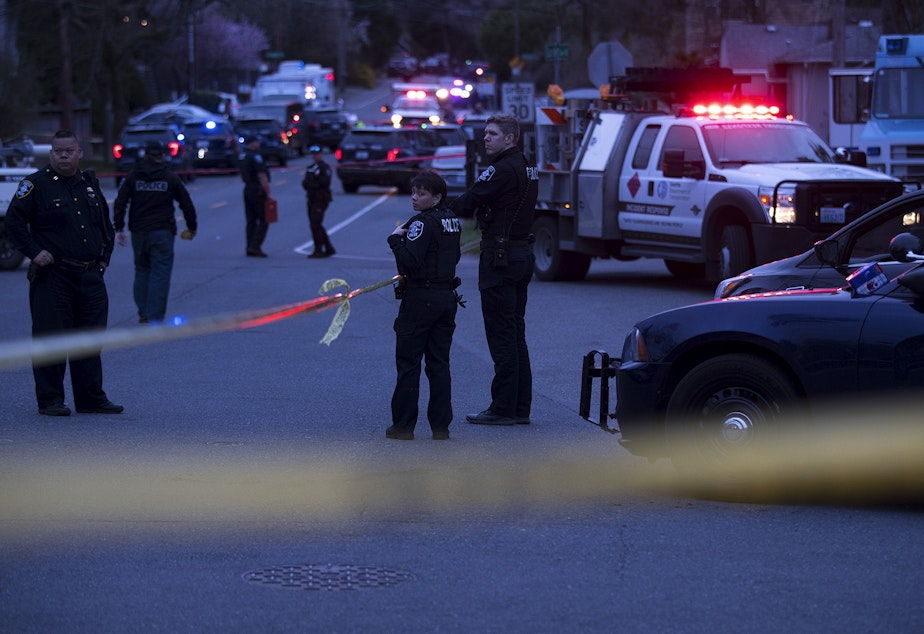 caption: Police investigate the scene of a fatal carjacking and shooting on Wednesday, March 27, 2019, at the intersection of 120th Street and Sandpoint Way Northeast in Seattle.