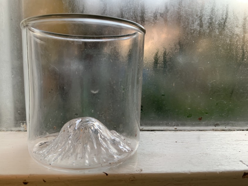 caption: A whiskey glass with the likeness of Mount Rainier peaking up from the bottom. 