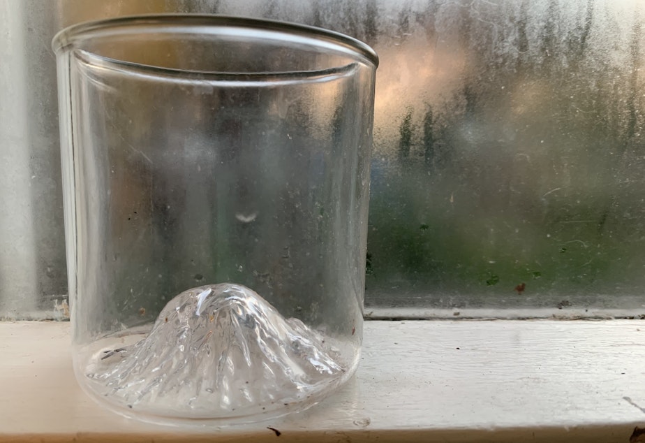 caption: A whiskey glass with the likeness of Mount Rainier peaking up from the bottom. 