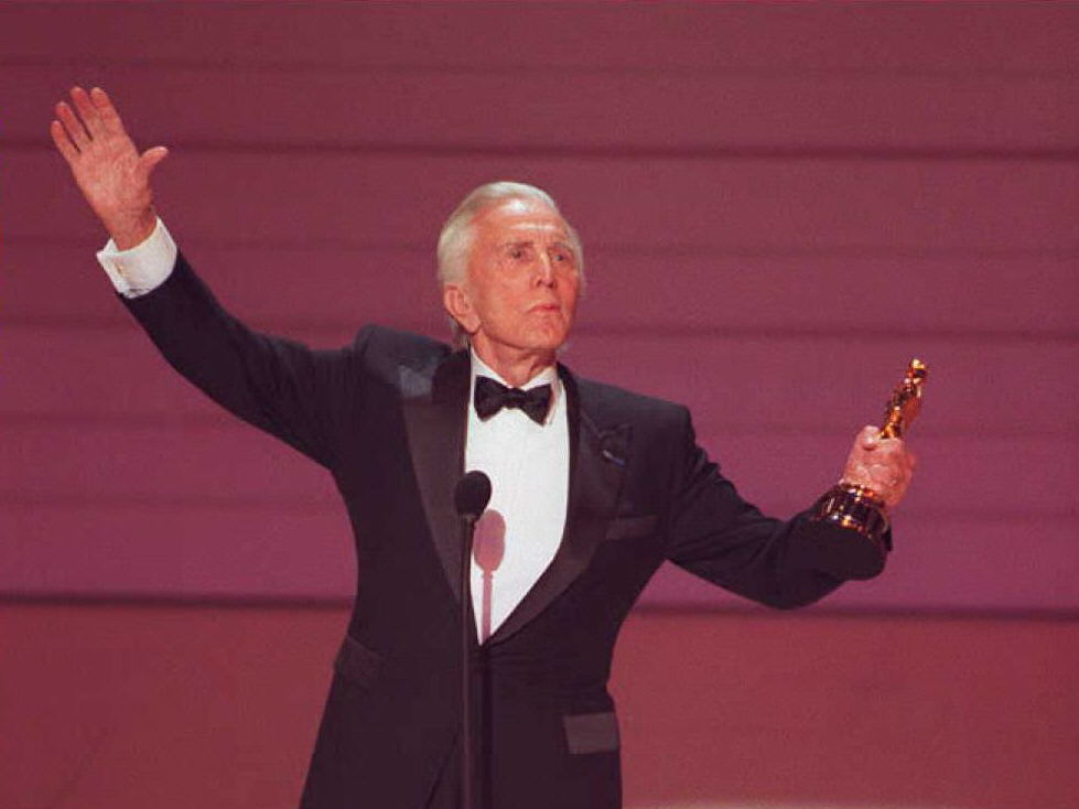 caption: US actor Kirk Douglas salutes the crowd at the 68th Annual Academy Awards after he received an Oscar for life time achievement.