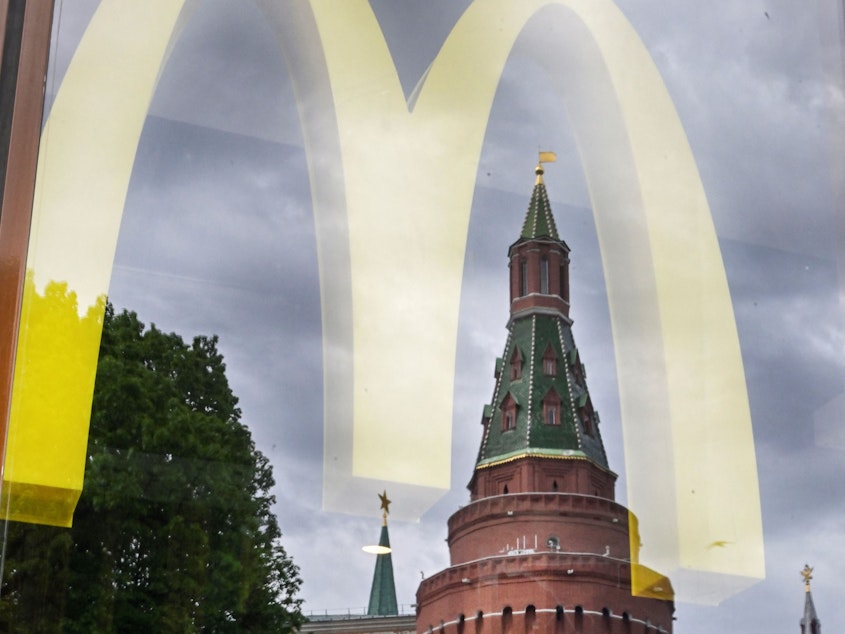 caption: People walk past a window of a McDonald's restaurant as the towers of the Kremlin reflect in it in Moscow on May 26, 2022.