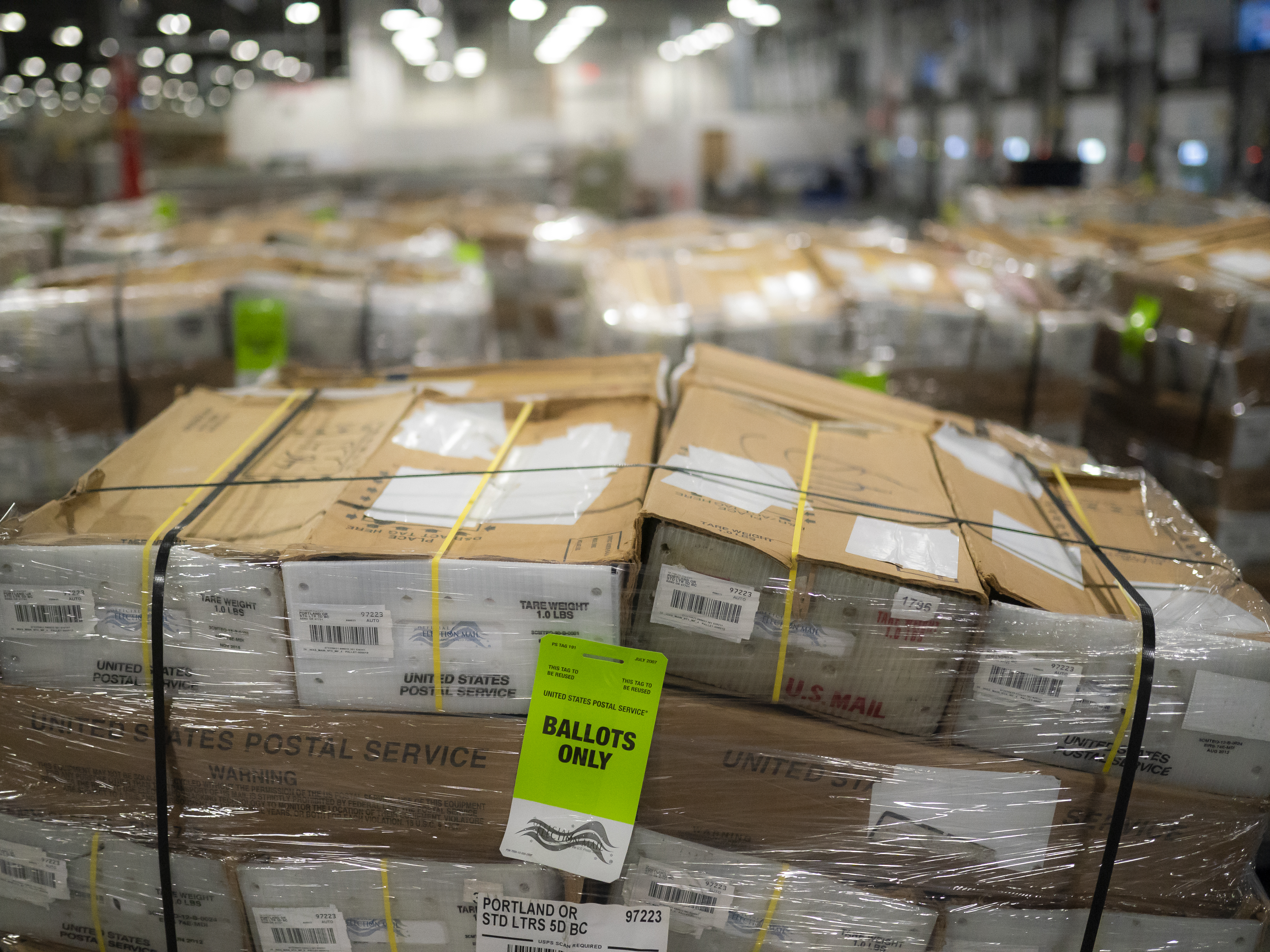 caption: Pallets filled with Washington and Oregon mail-in ballots fill an unloading area at a U.S. Postal Service processing and distribution center on Oct. 14, 2020, in Portland, Ore.