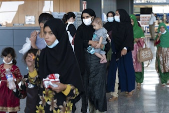 caption: Families evacuated from Kabul, Afghanistan, walk through the terminal before boarding a bus after they arrived at Washington Dulles International Airport, in Chantilly, Va., on Tuesday, Aug. 24, 2021.