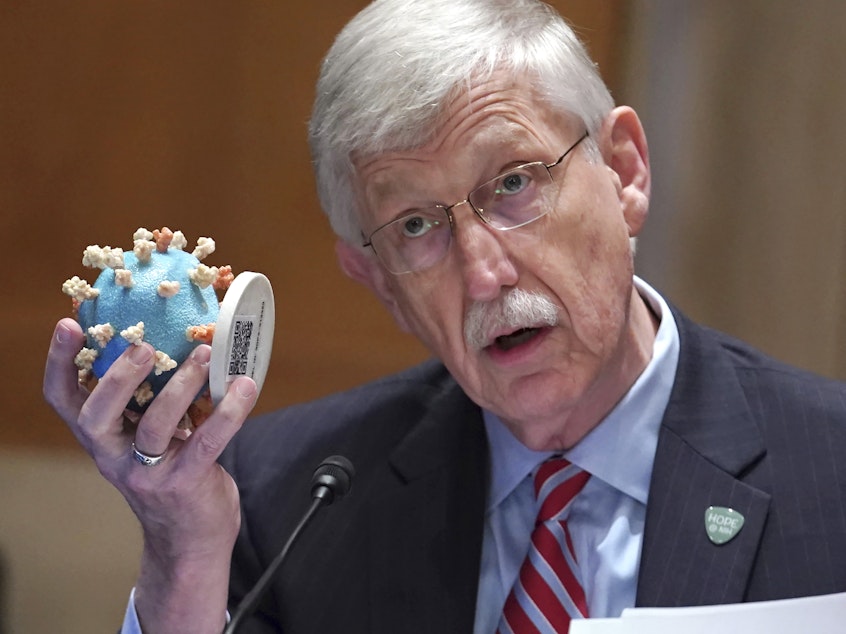 caption: NIH Director Dr. Francis Collins holds up a model of the coronavirus as he testifies before the Senate in May. Collins is retiring as director of the NIH.