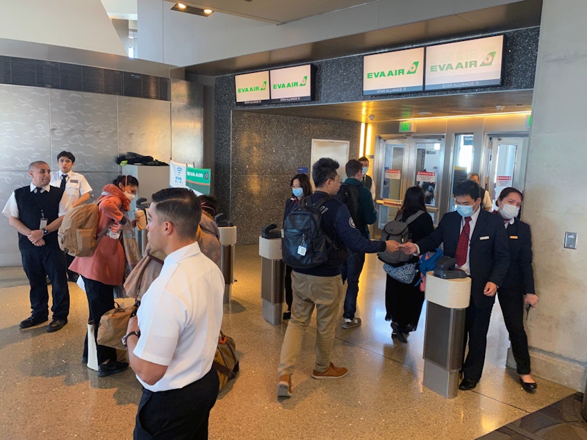 caption: Humans — workers and flight crews as well as passengers — can be exposed to any number of pathogens at airports. EVA Air employees are seen wearing face masks at the Los Angeles airport in February amid the coronavirus outbreak. U.S. officials advise masks are not the best way to mitigate one's risk of contracting the virus.