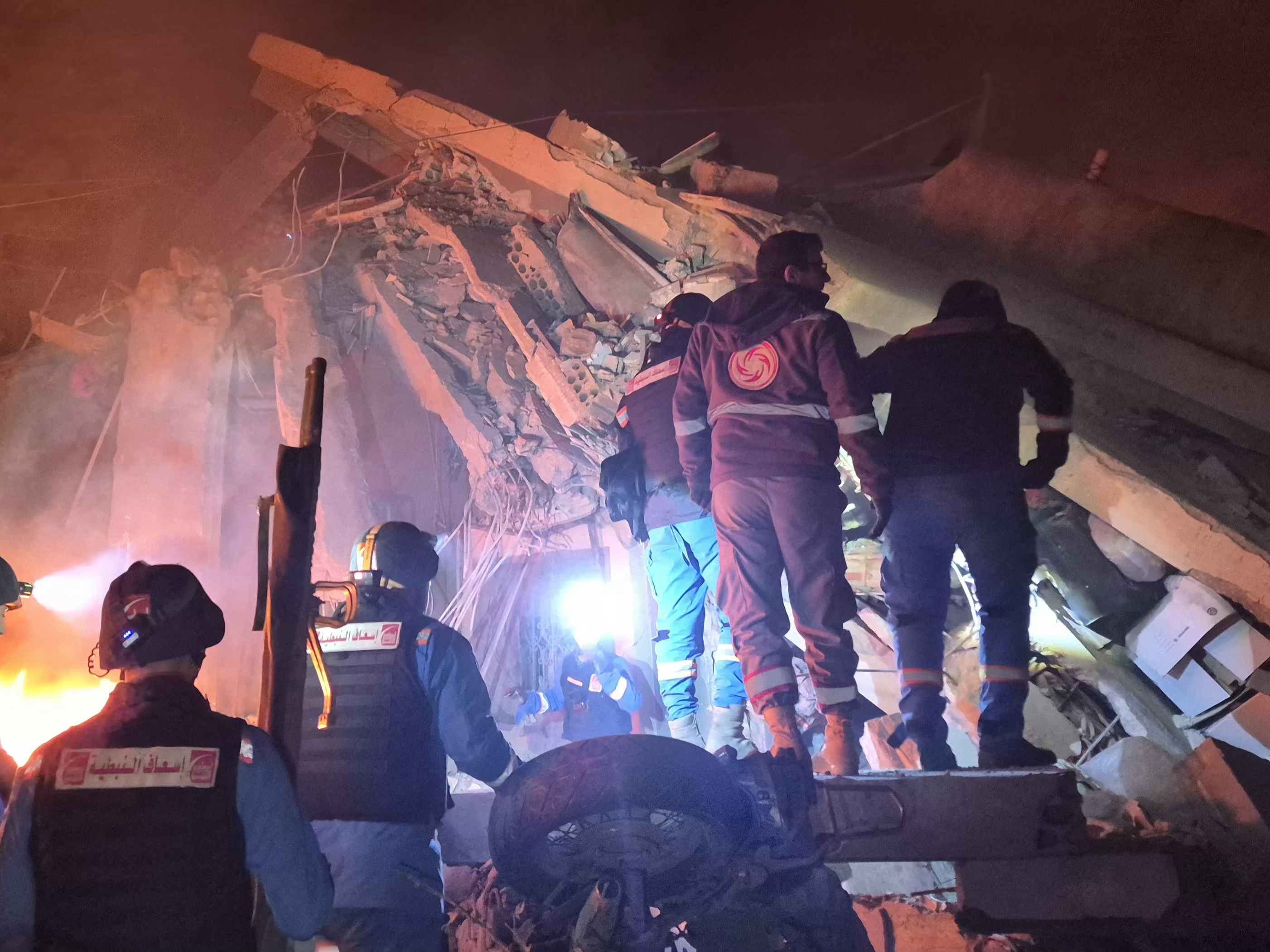 caption: First responders search under the rubble at the site of an Israeli airstrike in the village of Habbouch, southern Lebanon on April 10, 2026.