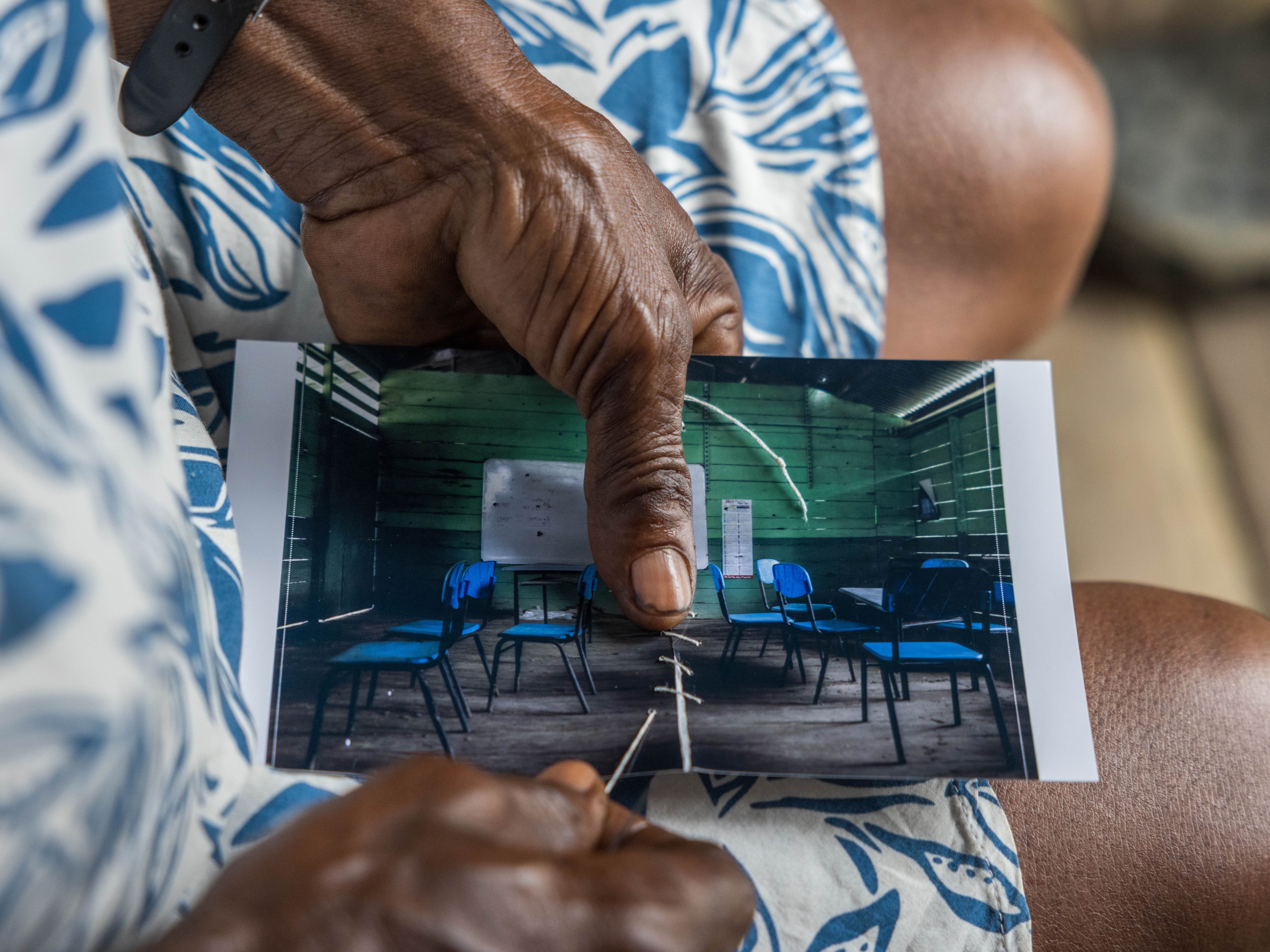 caption: Margarita Rojas Mena stitches up a torn photo of the local school, where armed groups had a confrontation — part of a healing ritual for residents. She's a healer in Mojaudó, a community in Alto Baudó, Chocó, Colombia.