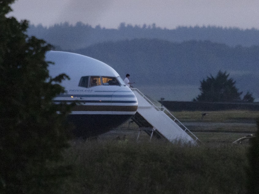 caption: A pilot gestures from the grounded EC-LZO Boeing 767 flight, initially meant to deport Rwandan asylum-seekers, at Boscombe Down Air Base in Boscombe Down, England, on June 14. The flight taking asylum-seekers from the U.K. to Rwanda was grounded at the last minute, after the intervention of the European Court of Human Rights.