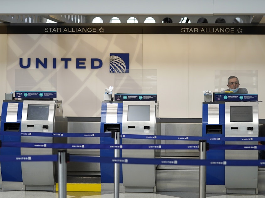 caption: United Airlines employees work at ticket counters at Chicago's O'Hare International Airport on Oct. 14. United and other airline stocks have been hard-hit by the pandemic economic slowdown.