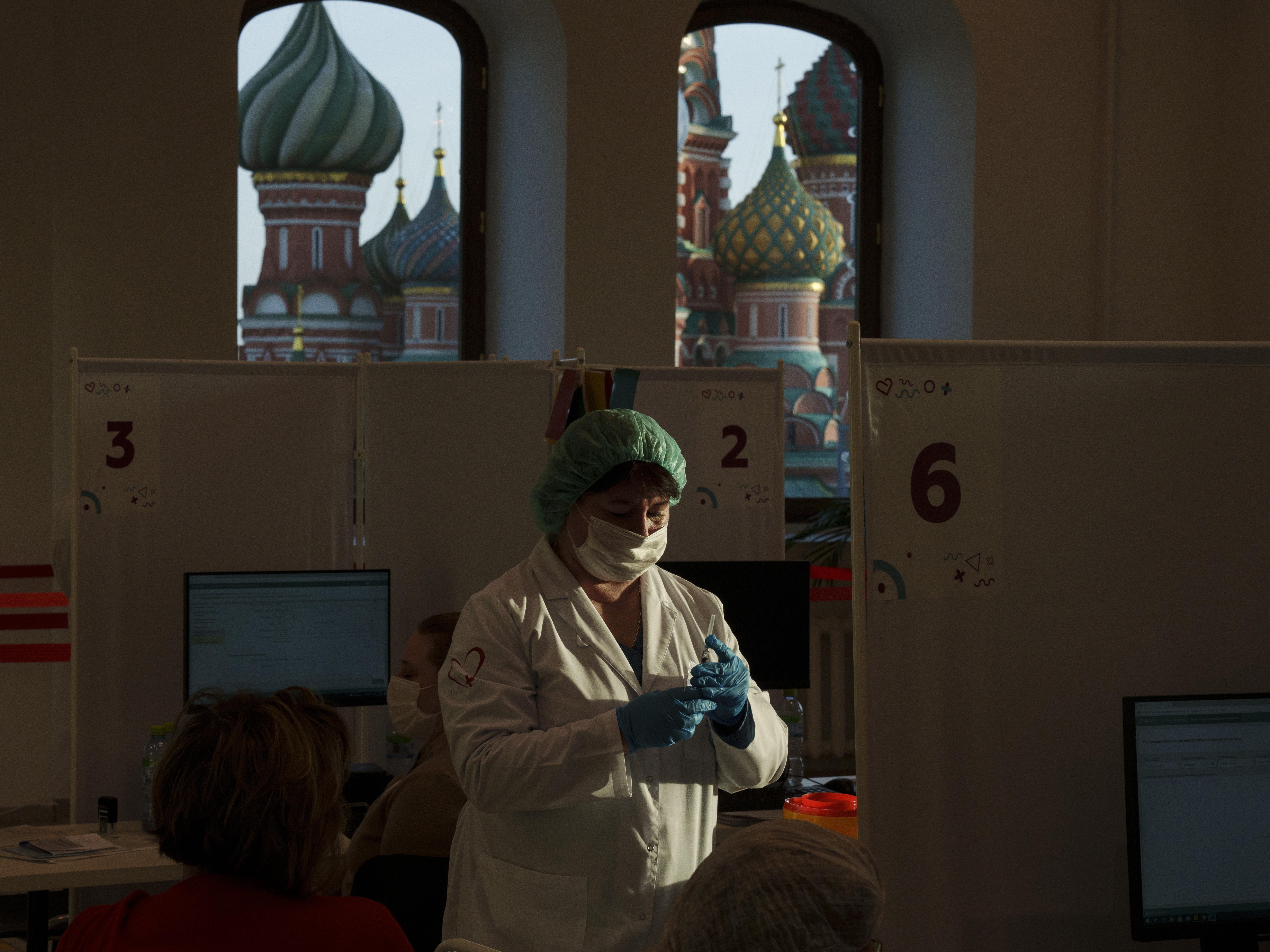 caption: A medical worker prepares a shot of Russia's Sputnik Lite coronavirus vaccine at a vaccination center last week in Moscow's GUM department store in Red Square with the St. Basil Cathedral in the background. The global death toll from COVID-19 has topped 5 million.