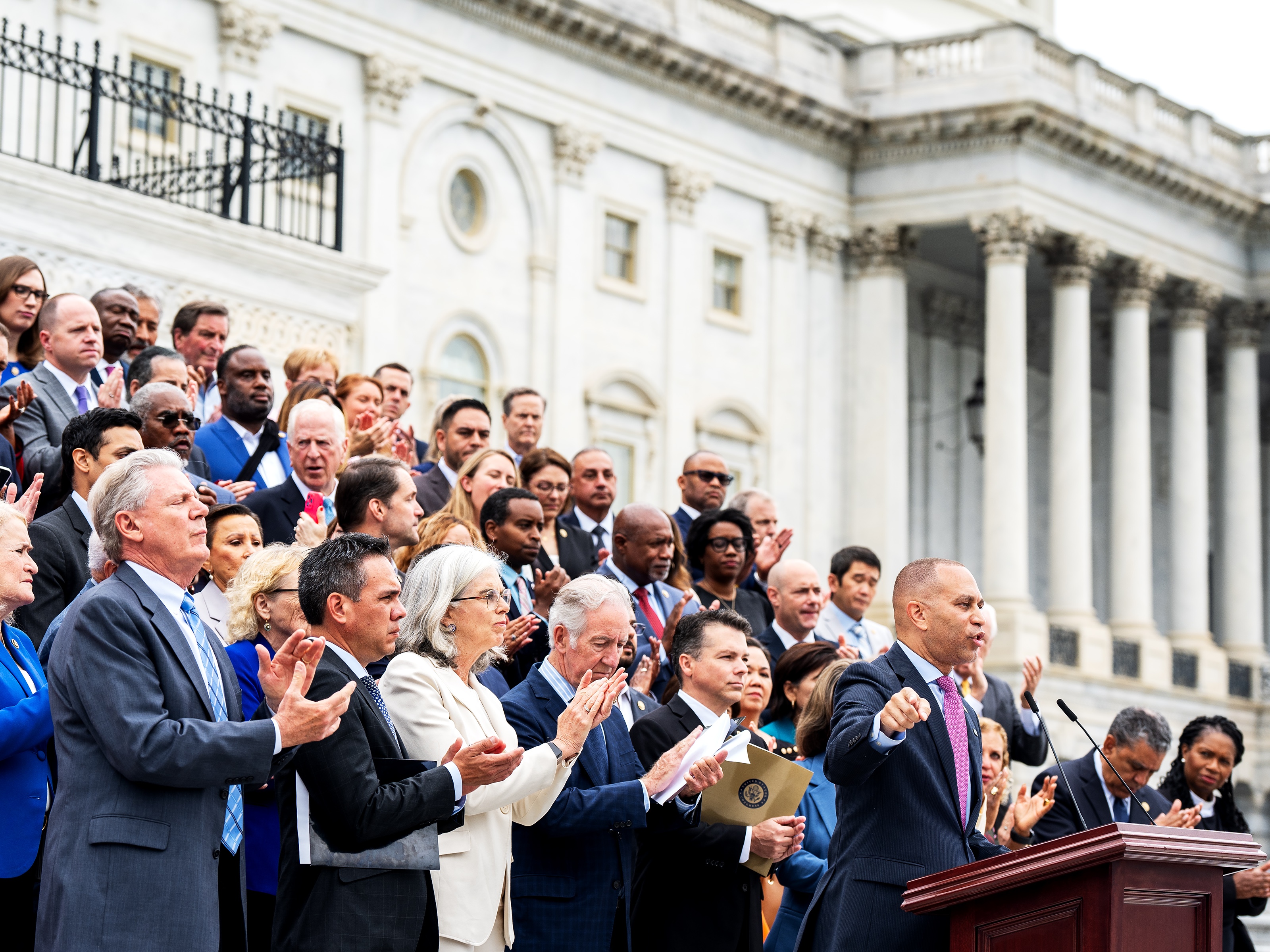 caption: House Minority Leader Hakeem Jeffries, D-N.Y., along with the House Democratic Caucus, assemble on the Capitol steps to rail against President Trump's signature bill of tax breaks and spending cuts on July 2.