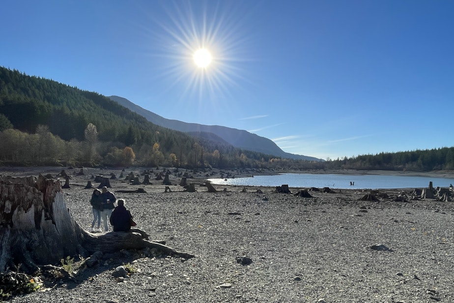 caption: Visitors stand on the dry lakebed of Rattlesnake Lake, an artificial water body created by leakage from Seattle Public Utilities' Chester Morse reservoir, on Nov. 17, 2023.