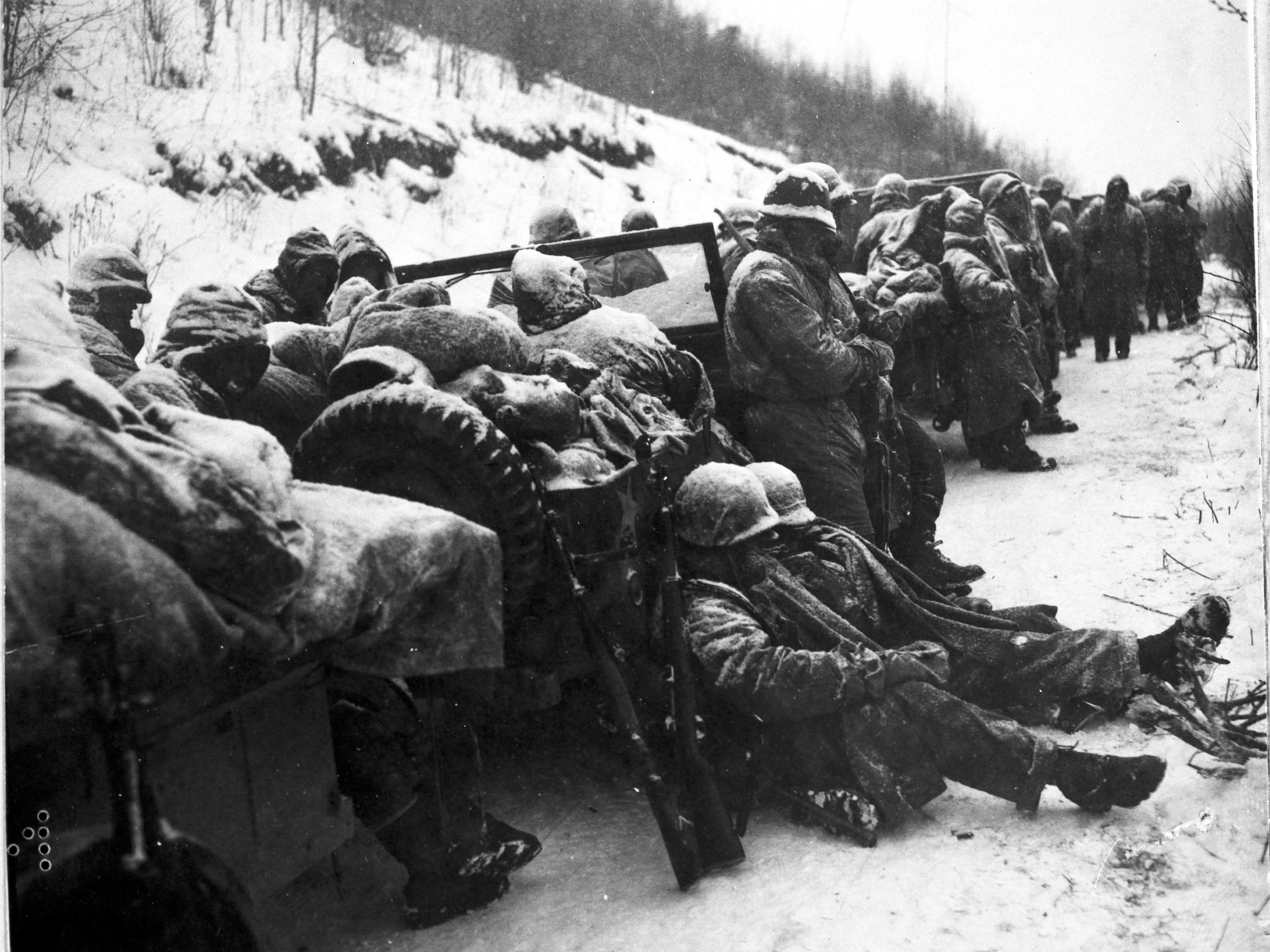 caption: Marines of the 5th and 7th regiments who hurled back a surprise onslaught by three Chinese communist divisions wait to withdraw from the Chosin Reservoir area circa December 1950.