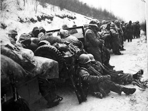 caption: Marines of the 5th and 7th regiments who hurled back a surprise onslaught by three Chinese communist divisions wait to withdraw from the Chosin Reservoir area circa December 1950.
