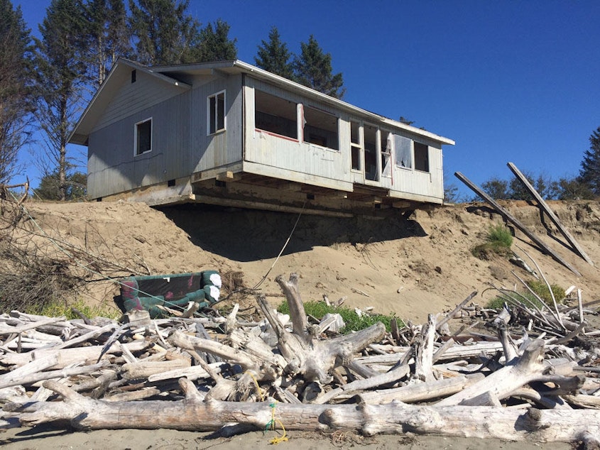 caption: Coastal erosion is washing away beachfront communities in Washington state. In 2018, reporter Tom Banse predicted this home at Washaway Beach, Washington, would be the next in a long series of homes to fall into the sea.