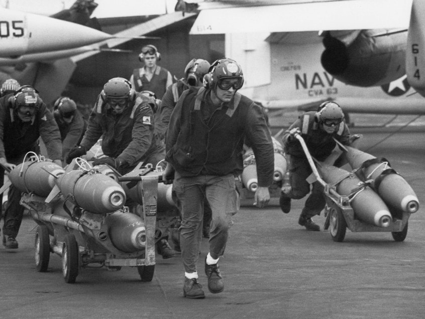 caption: U.S. Navy armorers wheel out 500-pound bombs for the wing racks of jets aboard the aircraft carrier USS Kitty Hawk in March 1971 off the coast of Vietnam.