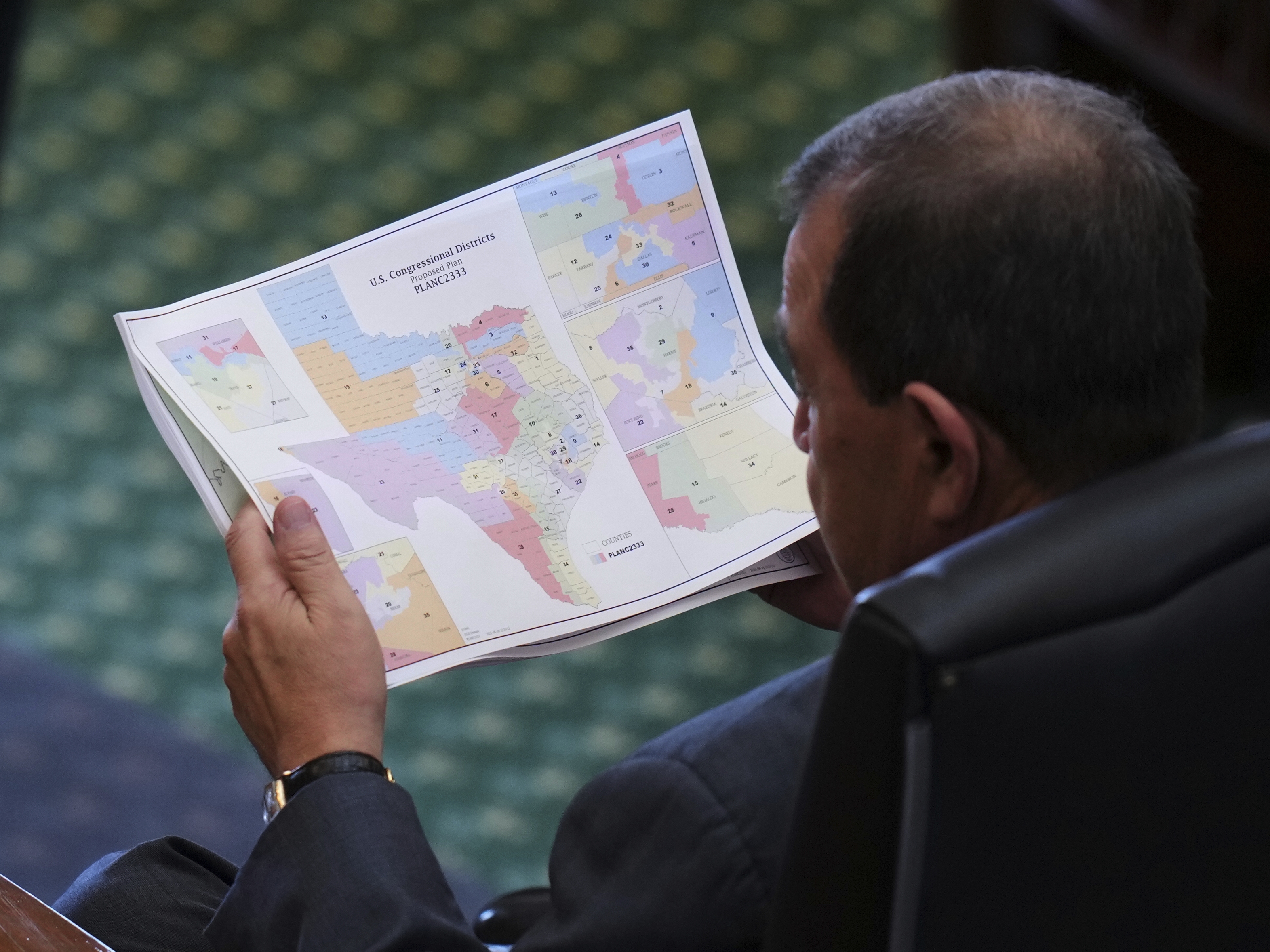 caption: Texas Republican state Sen. Pete Flores looks over the state's redrawn congressional map at the Texas Capitol in Austin in August.