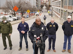 caption: Nashville Police Chief John Drake, center, speaks during a news conference on Christmas Day in Nashville. Law enforcement is looking into who and how many may have been involved in a bombing in the city's downtown corridor.