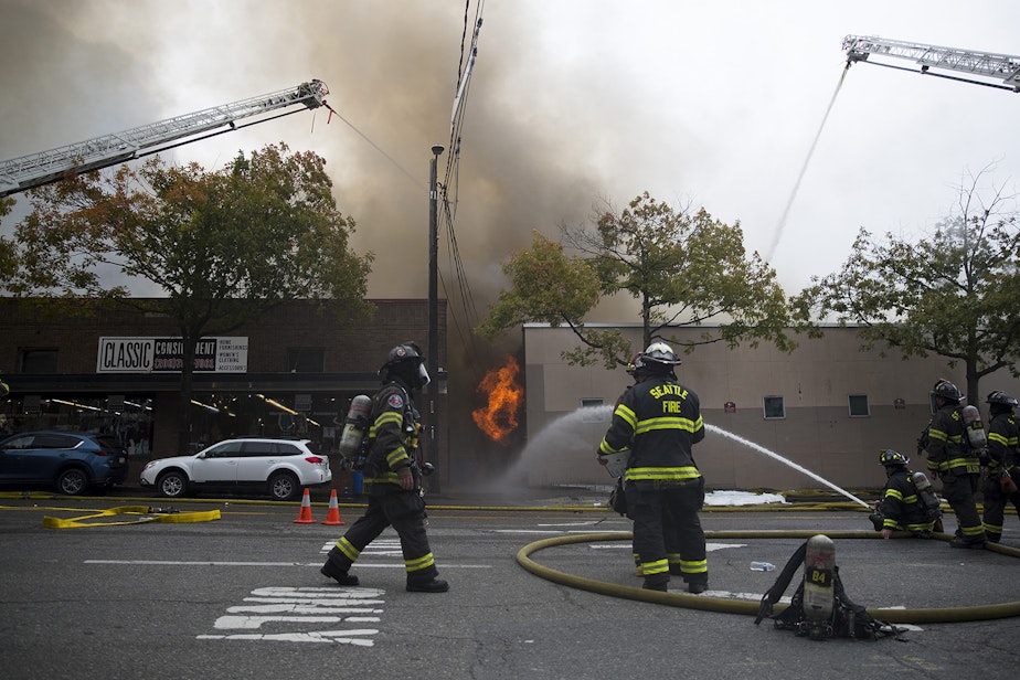 caption: Firefighters work to put out a fire at Kitchen 'N Things on Monday, October 7, 2019, at the intersection of NW Market Street and 24th Avenue Northwest in Seattle.