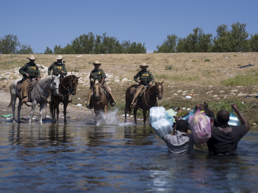 caption: U.S. Border Patrol agents on horseback block migrants crossing the Rio Grande on Sunday near the Del Rio-Acuña Port of Entry in Del Rio, Texas. Horse patrols at that part of the border have been suspended, the White House press secretary says.