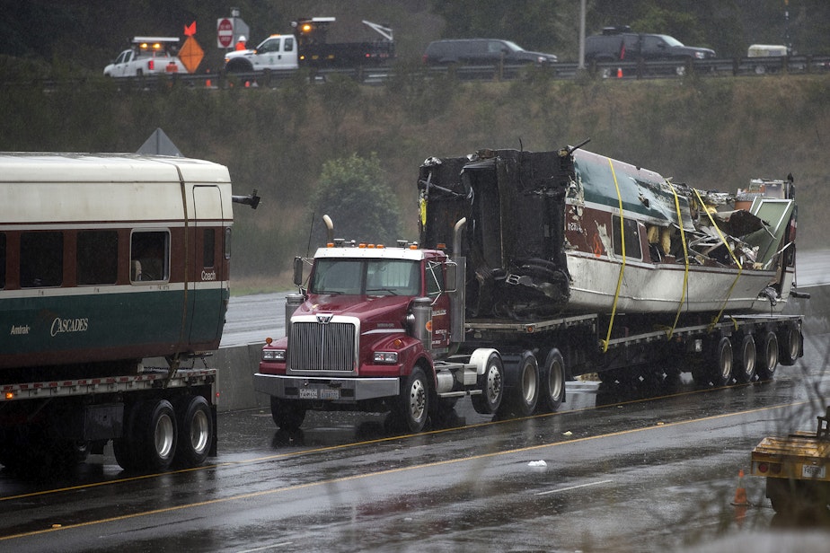 caption: A damaged train car is shown on the bed of a truck along I-5 South on Tuesday, December 19, 2017, in Dupont.