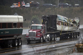 caption: A damaged train car is shown on the bed of a truck along I-5 South on Tuesday, December 19, 2017, in Dupont. 